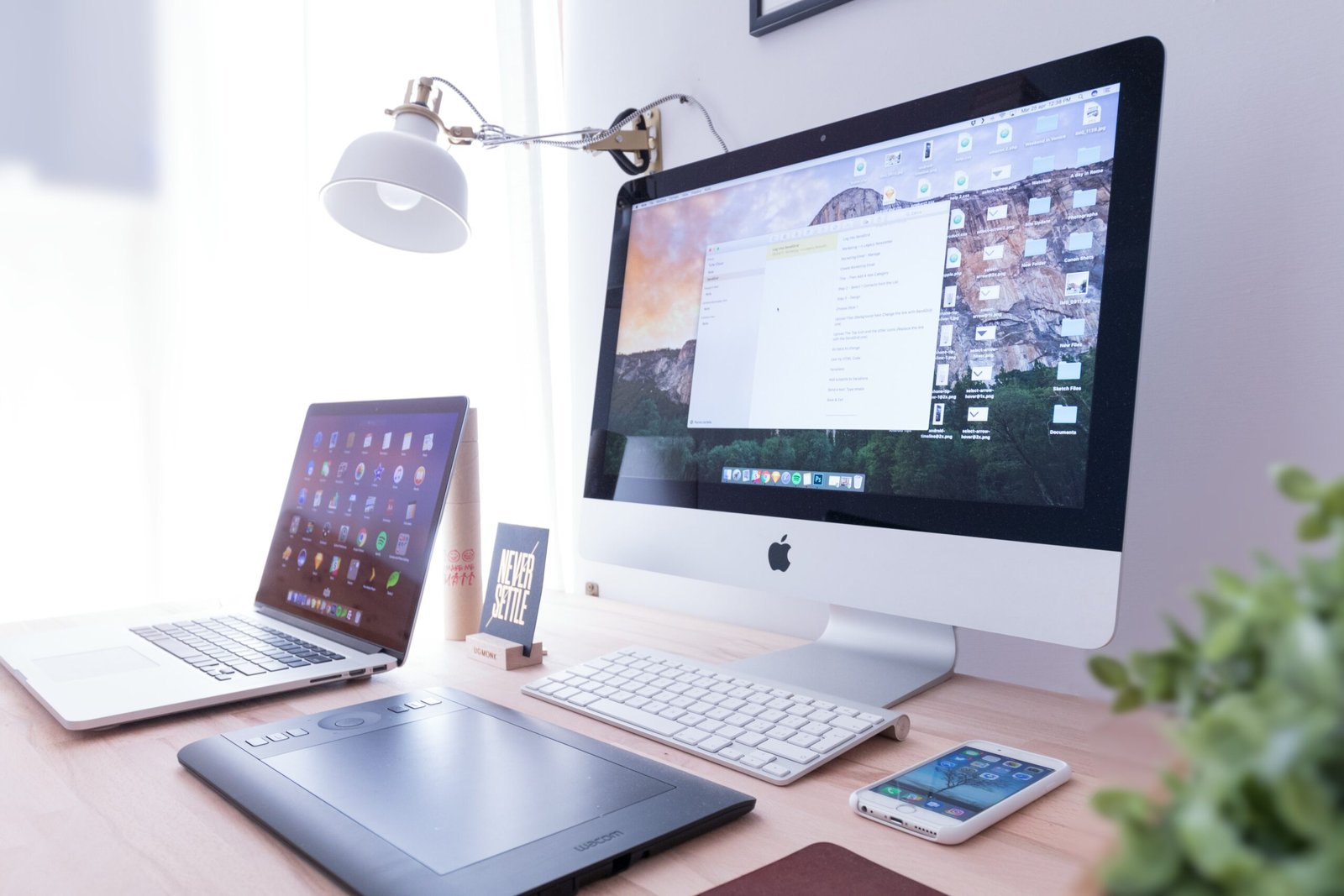 silver iMac near iPhone on brown wooden table