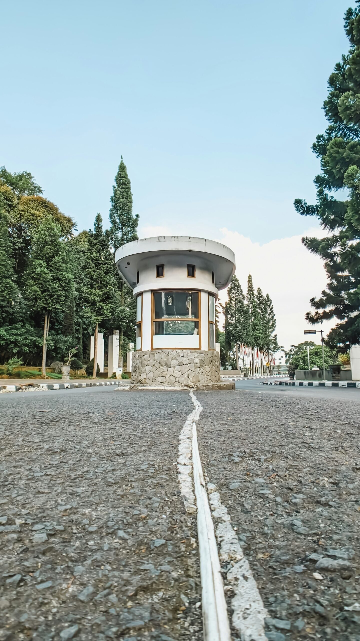 A round building with a white roof on a gravel road